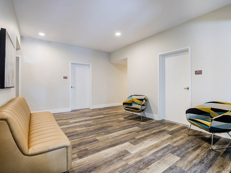 Lobby with Tan Sofa, Hardwood Inspired Floor, White Walls and Yellow/Dark Blue Chairs